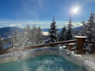 Troadkasten © Familie Ebner Blick von der Almhütte Troadkasten ins Tal. Ein Whirlpool steht auf der Terrasse von der Hütte. Wunderschönes Winterwetter mit angeschneiten Bäumen