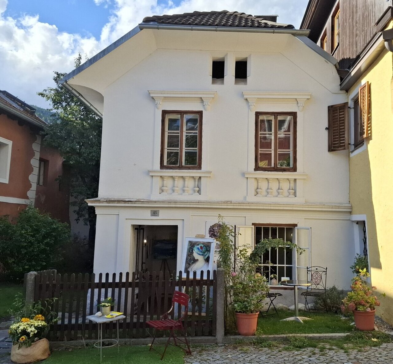 Ein weißes Haus mit braunen Fenstern und kleinem Vorgarten