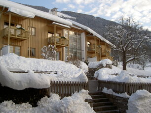 Ferienwohnungen mit einer Holzfassade und großen Fensterfronten im verschneiten Winter.