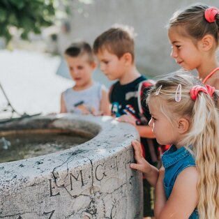 Vier Kinder schauen in einen Brunnen