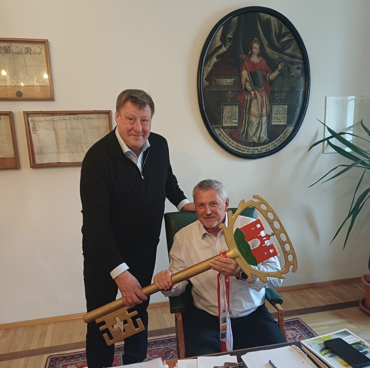 Am Bild ist Altbürgermeister Josef Jury mit dem 1. Vizebürgermeister Claus Faller im Bürgermeisterzimmer der Stadt Gmünd zu sehen. Altbürgermeister Josef Jury übergibt symbolisch den großen Schlüssel der Stadtgemeinde Gmünd an den 1. Vizebürgermeister Claus Faller