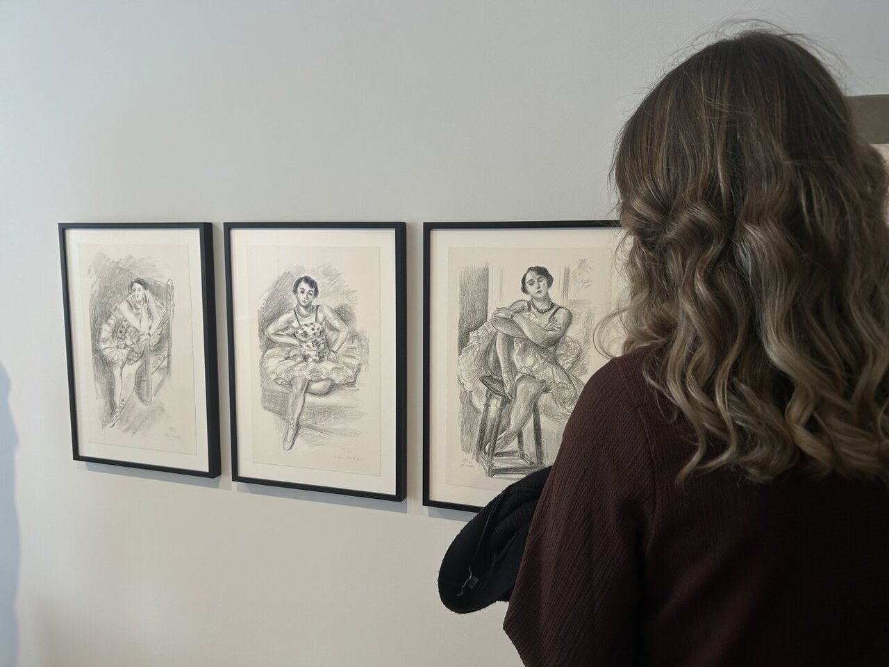 Eine Dame schaut Gemälde an einer Wand an
